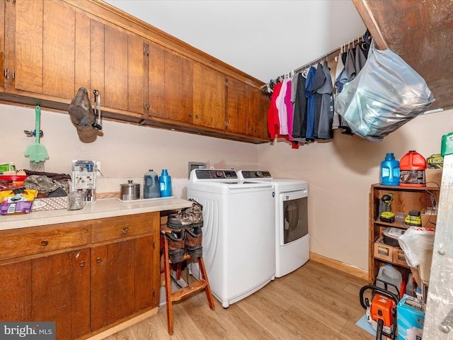 laundry room featuring washer and clothes dryer, cabinets, and light wood-type flooring