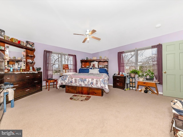 carpeted bedroom with multiple windows, ceiling fan, and a baseboard heating unit