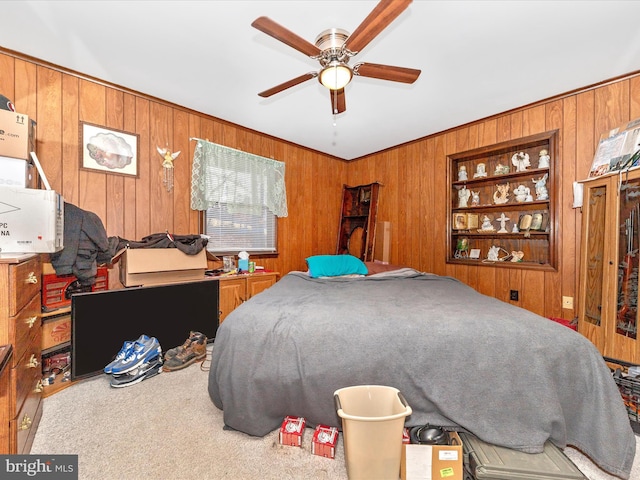 bedroom with carpet flooring, ceiling fan, and wooden walls