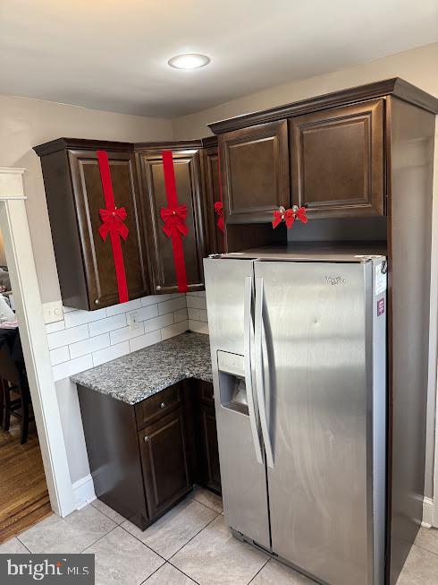 kitchen with tasteful backsplash, dark brown cabinetry, light tile patterned floors, and stainless steel refrigerator with ice dispenser