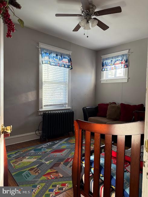 bedroom with multiple windows, ceiling fan, and radiator heating unit