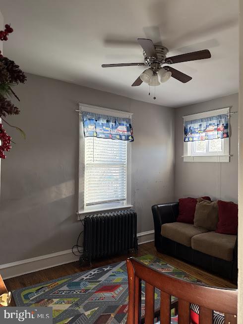 living room featuring wood-type flooring, radiator, and ceiling fan