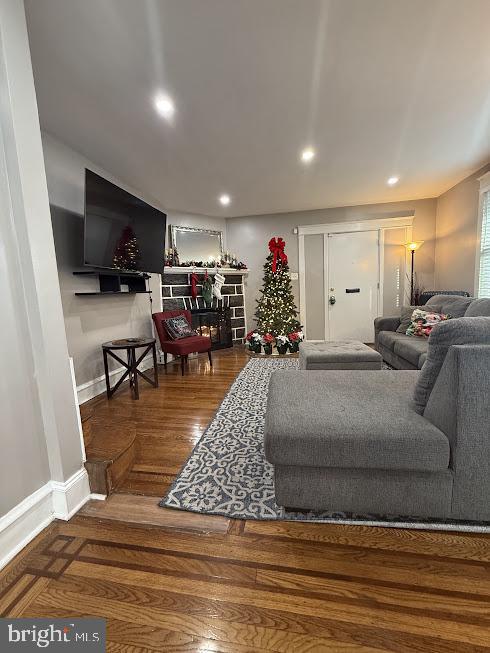 living room with hardwood / wood-style floors and a stone fireplace