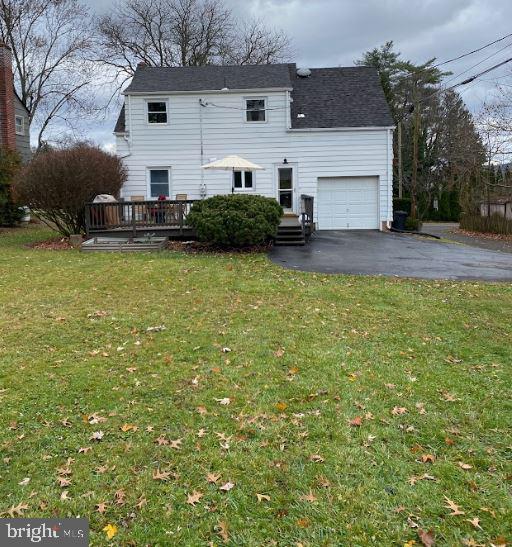 back of house with a garage, a deck, and a lawn