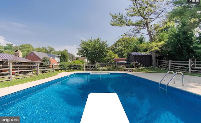 view of swimming pool with a shed and a diving board