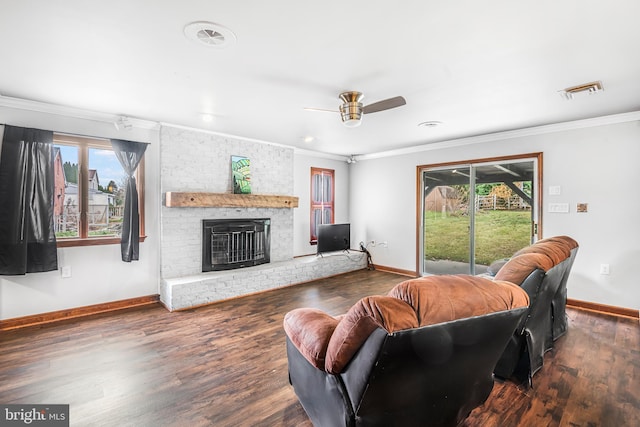 living room featuring crown molding, ceiling fan, a fireplace, and dark wood-type flooring