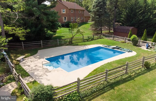 view of swimming pool with a patio, a rural view, and a lawn