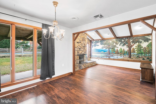 unfurnished living room featuring a fireplace, lofted ceiling with beams, dark wood-type flooring, and a notable chandelier