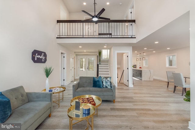 living room with ceiling fan, light hardwood / wood-style floors, and a high ceiling