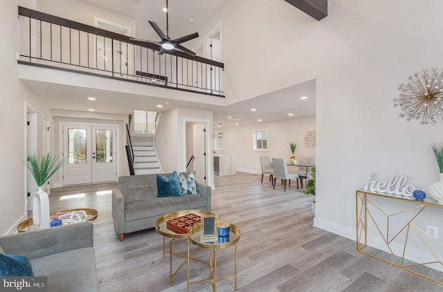 living room with a towering ceiling, light hardwood / wood-style floors, and ceiling fan