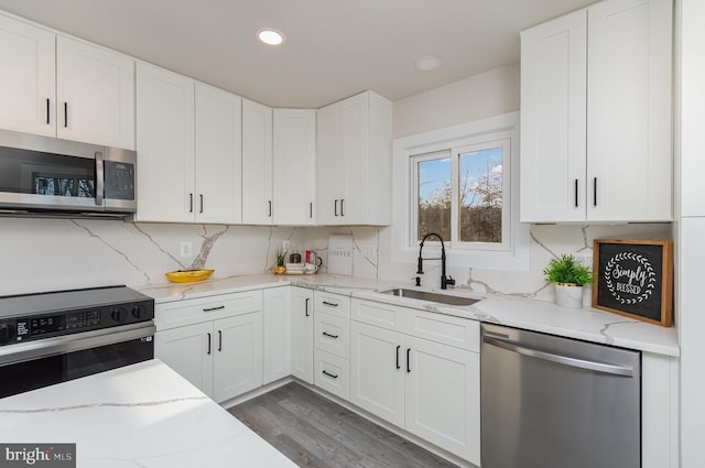 kitchen featuring sink, light stone counters, appliances with stainless steel finishes, dark hardwood / wood-style flooring, and white cabinetry