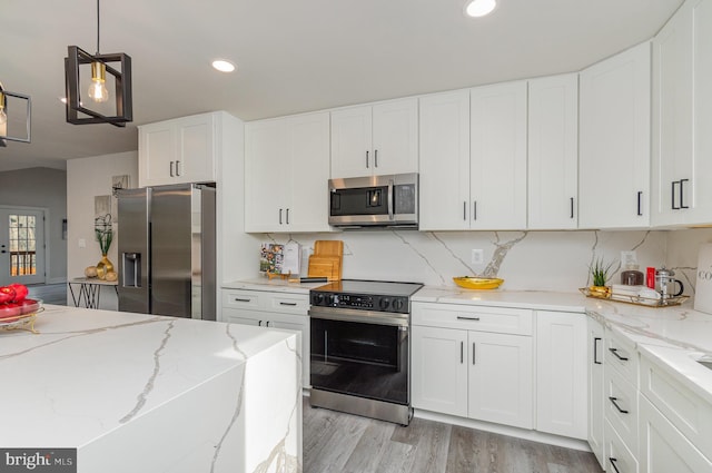 kitchen featuring light stone counters, appliances with stainless steel finishes, pendant lighting, white cabinets, and light wood-type flooring