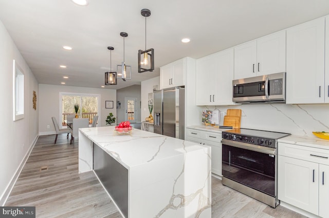 kitchen with white cabinets, light wood-type flooring, stainless steel appliances, and a kitchen island