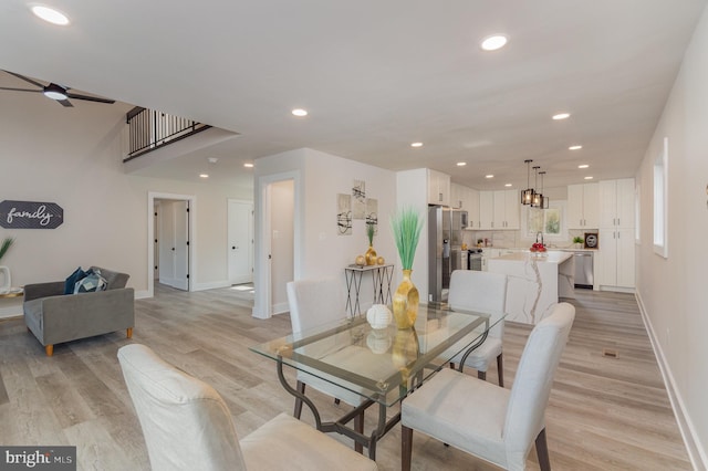 dining space with ceiling fan and light wood-type flooring