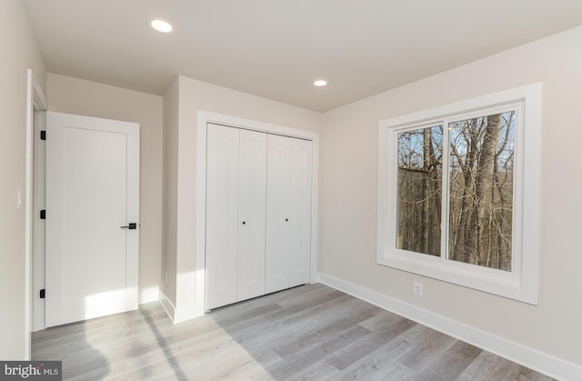 unfurnished bedroom featuring light wood-type flooring and a closet