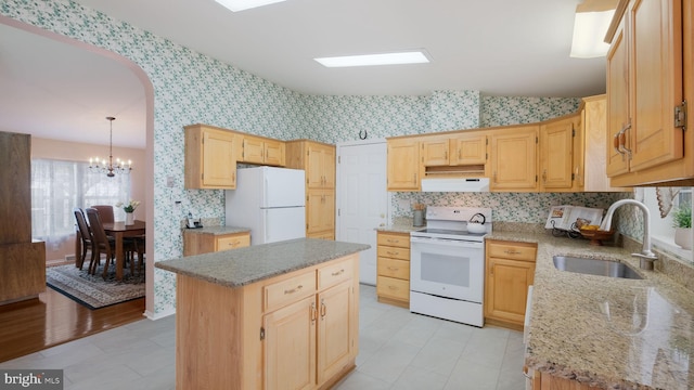 kitchen with white appliances, sink, light hardwood / wood-style flooring, a notable chandelier, and a kitchen island