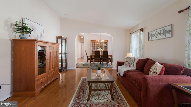 living room featuring light hardwood / wood-style floors, vaulted ceiling, and a notable chandelier