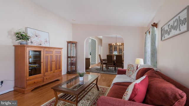 living room featuring wood-type flooring, lofted ceiling, and a chandelier