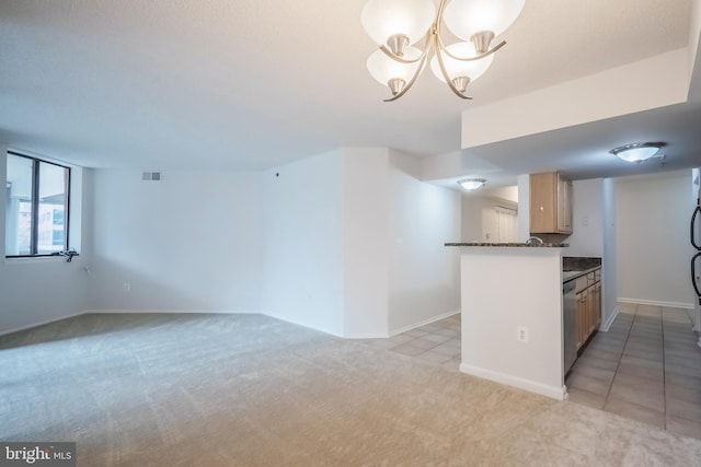 kitchen featuring light brown cabinets, hanging light fixtures, light colored carpet, kitchen peninsula, and a chandelier