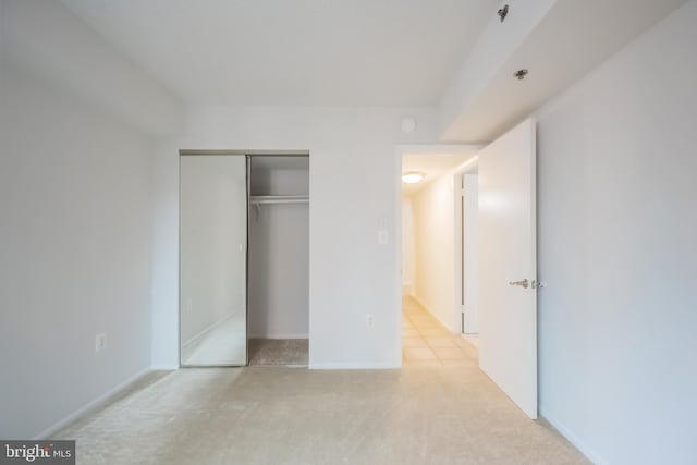 unfurnished bedroom with a closet and light colored carpet