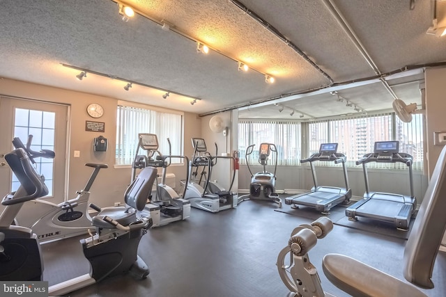 gym with a textured ceiling, a wealth of natural light, and track lighting