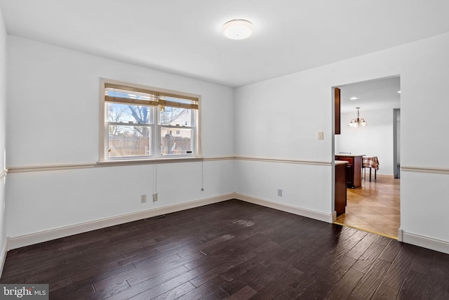 empty room featuring a chandelier and dark hardwood / wood-style floors