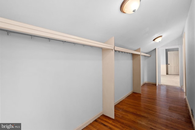 walk in closet with dark hardwood / wood-style flooring and vaulted ceiling