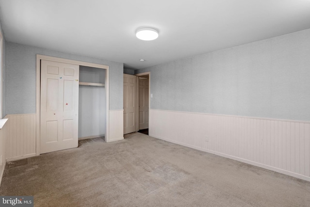 unfurnished bedroom with a closet and light colored carpet