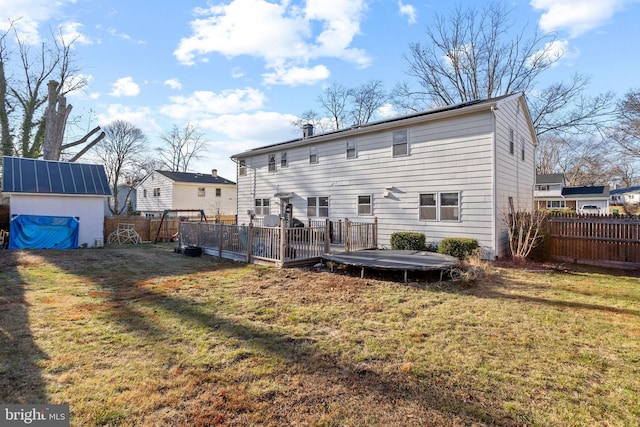 rear view of property featuring a shed, a deck, and a lawn