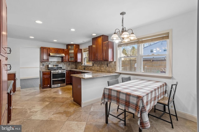 kitchen with backsplash, hanging light fixtures, stainless steel stove, light stone countertops, and kitchen peninsula