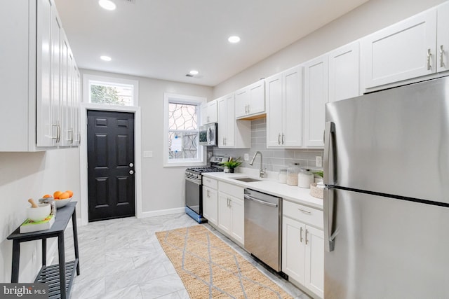 kitchen featuring white cabinets, appliances with stainless steel finishes, tasteful backsplash, and sink