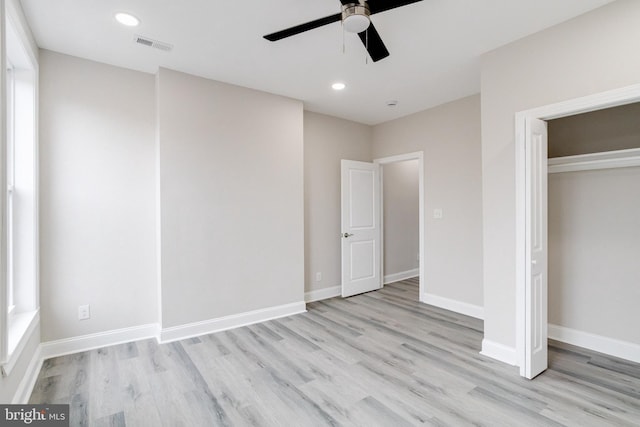 unfurnished bedroom featuring ceiling fan, a closet, multiple windows, and light hardwood / wood-style flooring