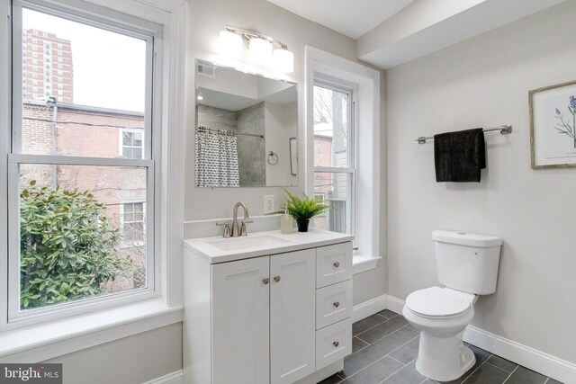 bathroom with tile patterned flooring, vanity, toilet, and walk in shower