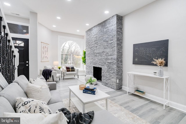 living room featuring a stone fireplace and light hardwood / wood-style flooring