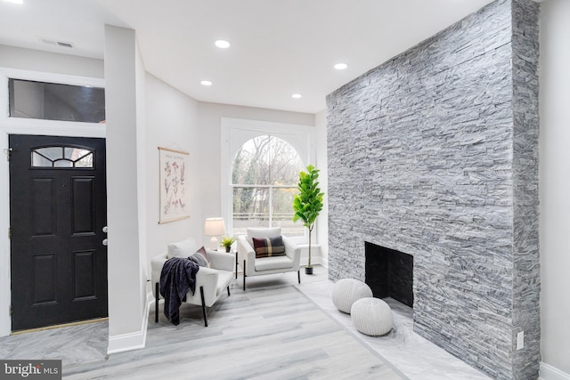 foyer entrance with light hardwood / wood-style flooring and a stone fireplace