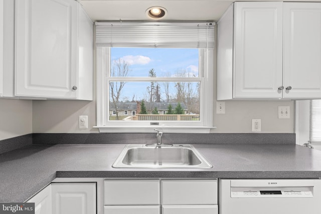 kitchen with dishwasher, white cabinetry, and sink