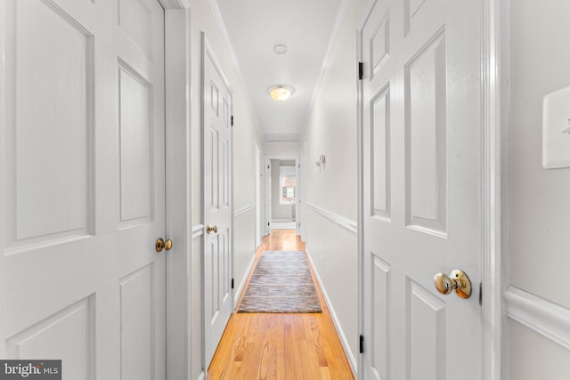 corridor with light hardwood / wood-style floors and crown molding