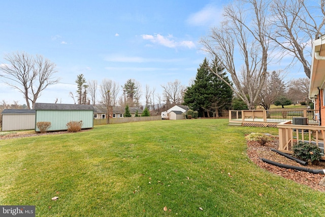 view of yard with central AC unit, a shed, and a wooden deck