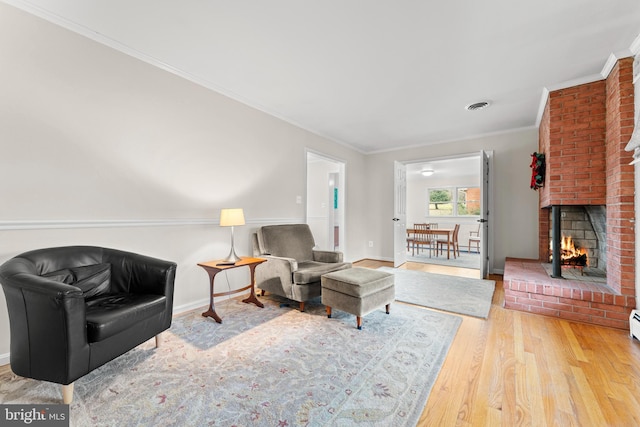 living room featuring hardwood / wood-style floors, ornamental molding, and a brick fireplace