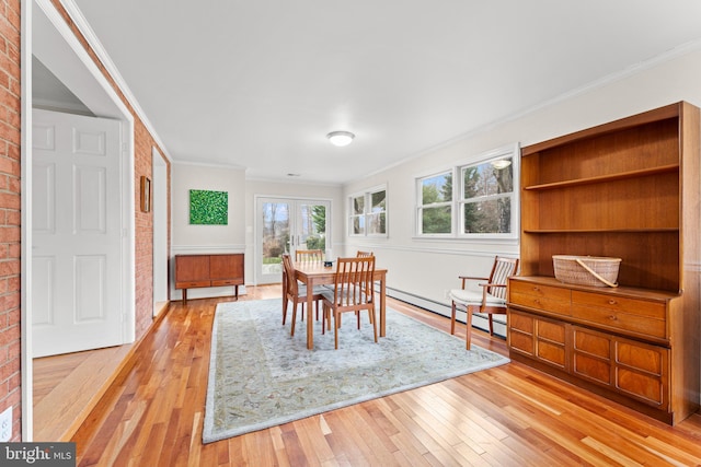 dining room featuring baseboard heating, crown molding, and light hardwood / wood-style flooring