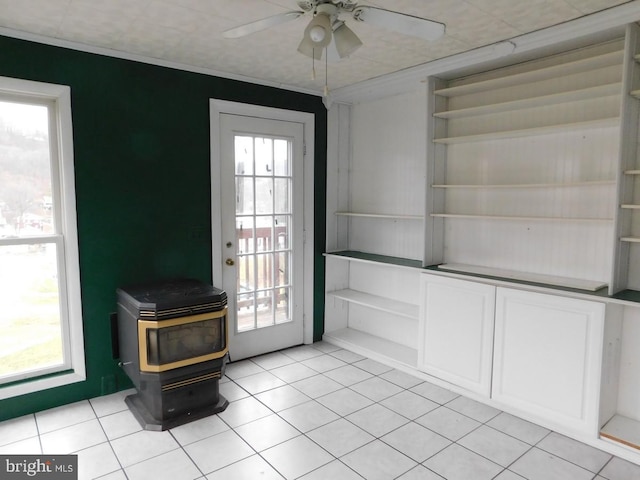 entryway featuring ceiling fan, a wood stove, and light tile patterned floors