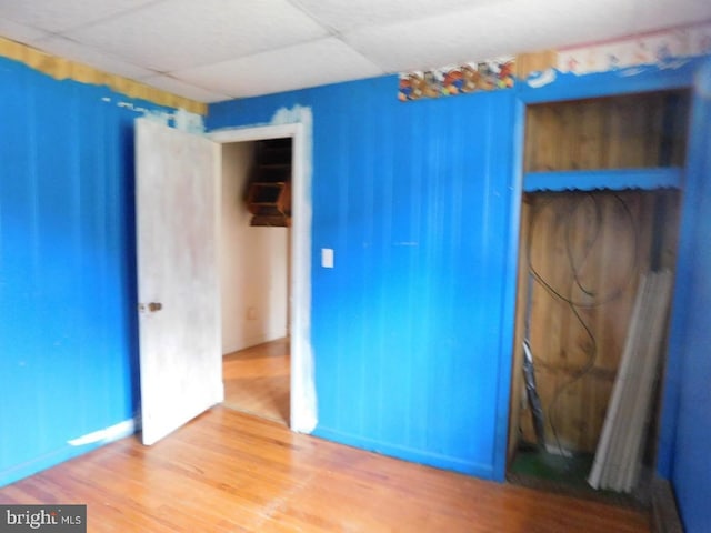 unfurnished bedroom featuring hardwood / wood-style floors and a drop ceiling