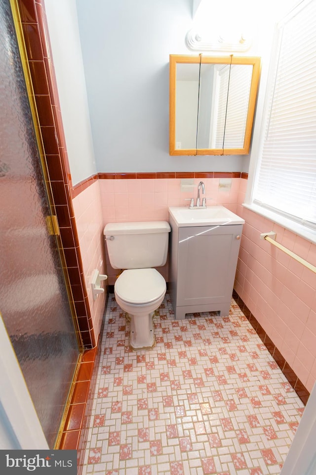 bathroom featuring tile walls, vanity, toilet, and walk in shower