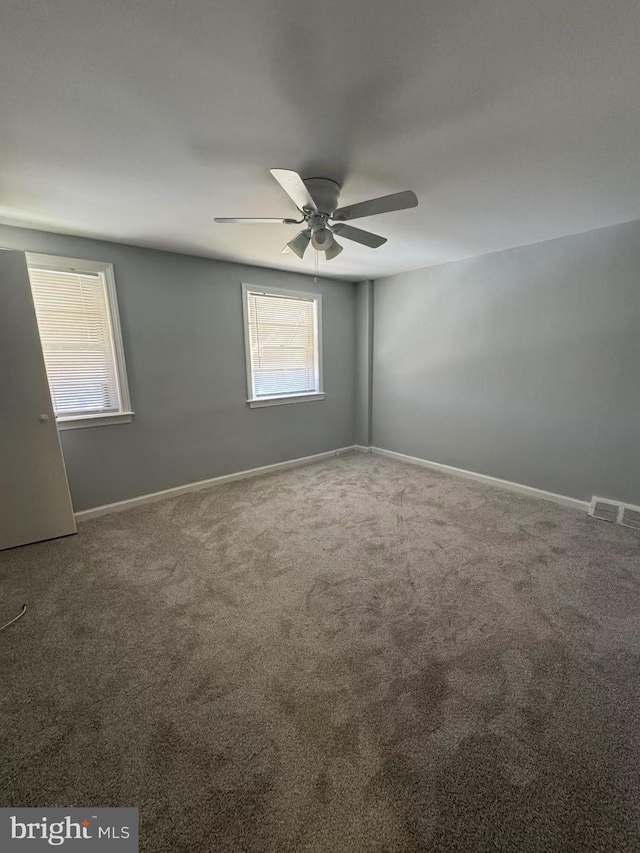 empty room featuring ceiling fan, plenty of natural light, and carpet