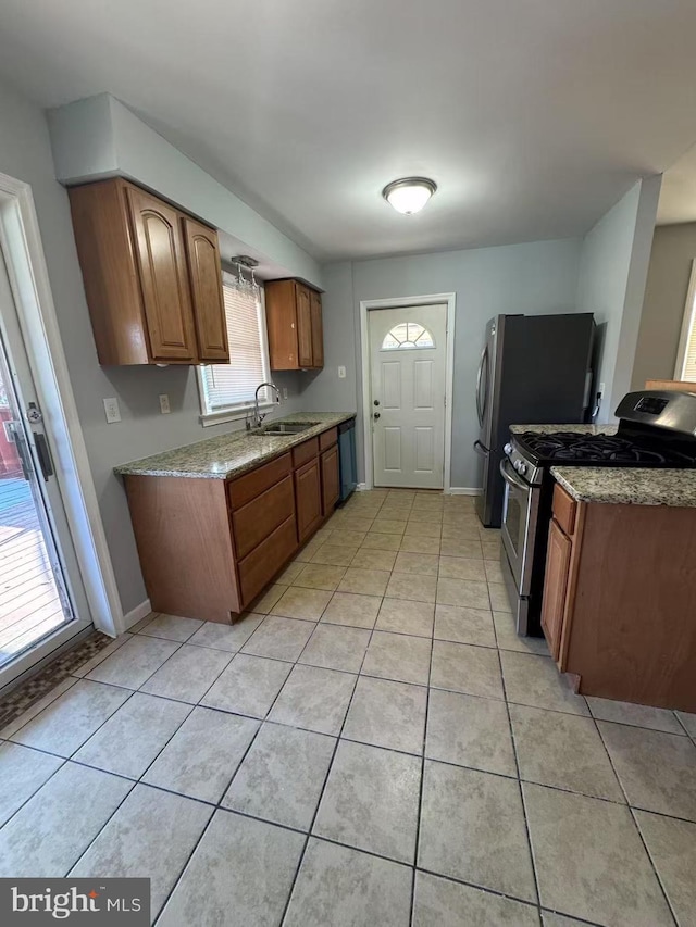 kitchen featuring stainless steel gas stove, sink, a wealth of natural light, and light tile patterned flooring