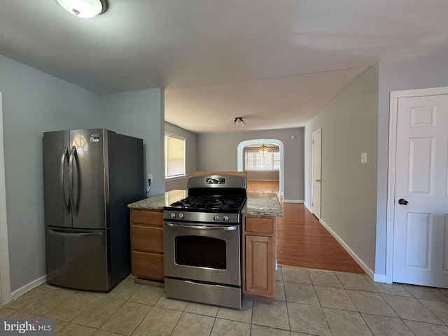 kitchen with light stone countertops, light tile patterned floors, and stainless steel appliances