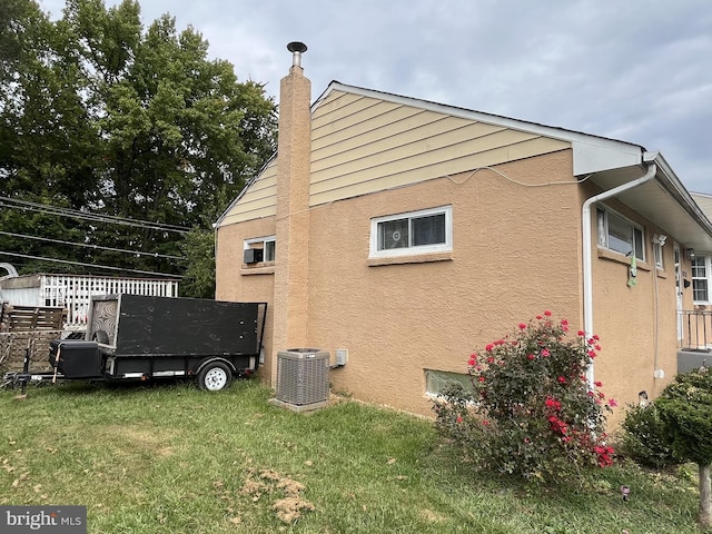 view of side of home with central AC unit and a lawn