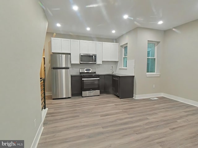 kitchen featuring white cabinetry, sink, light wood-type flooring, and appliances with stainless steel finishes