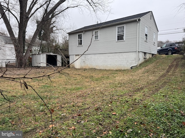 view of side of home featuring a yard and a storage unit