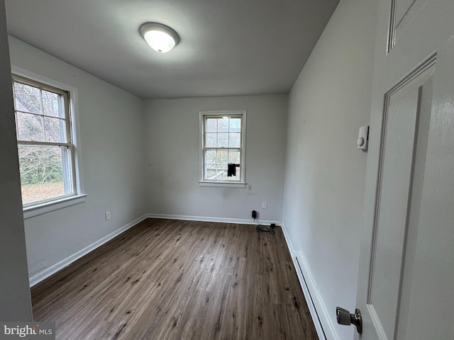 unfurnished room with hardwood / wood-style flooring and baseboard heating